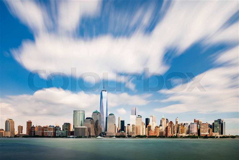 The cityscape of New York as viewed from New Jersey with running clouds on bright blue sky, stock photo
