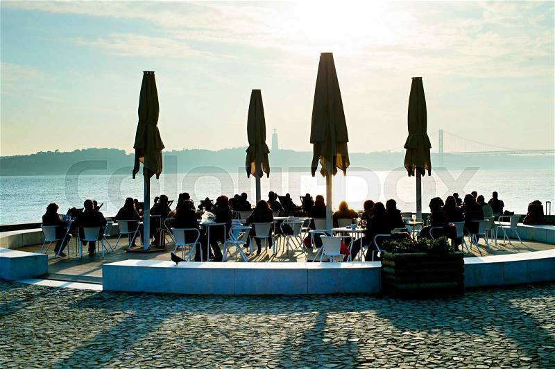 People in outdoor restaurant on embankment of Lisbon, Portugal, stock photo
