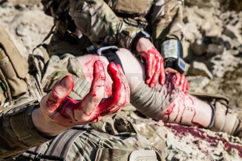 United States Army ranger medic treating the wounds of his injured fellow in arms in the mountains, stock photo