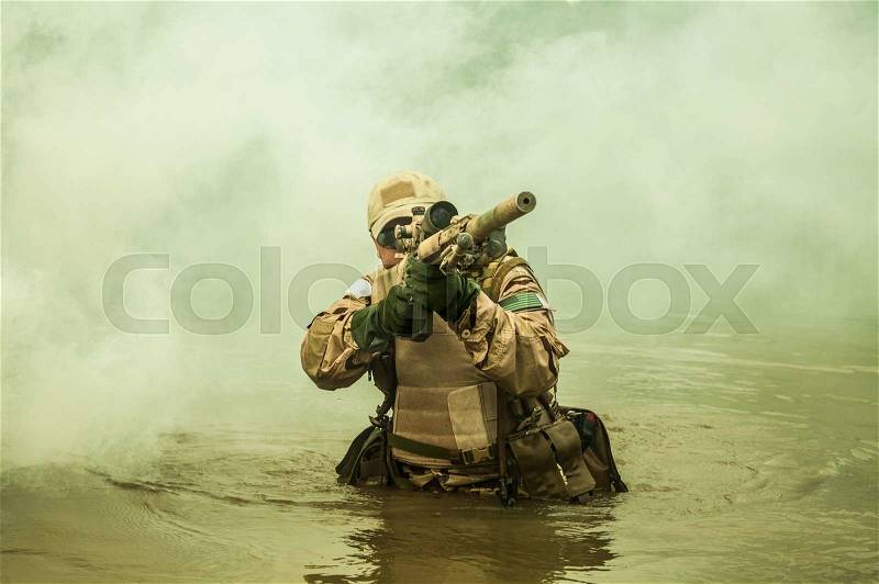 Member of Navy SEAL Team crossing the river with weapons, stock photo