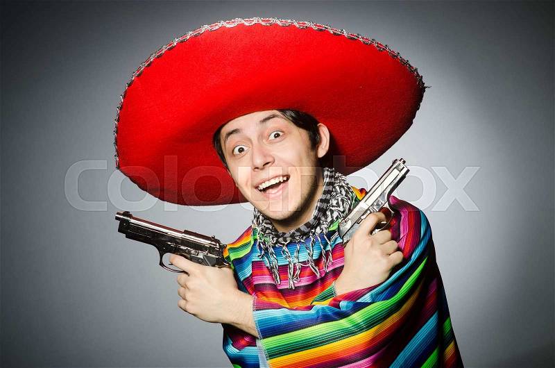 Man in vivid mexican poncho holding handgun against gray, stock photo