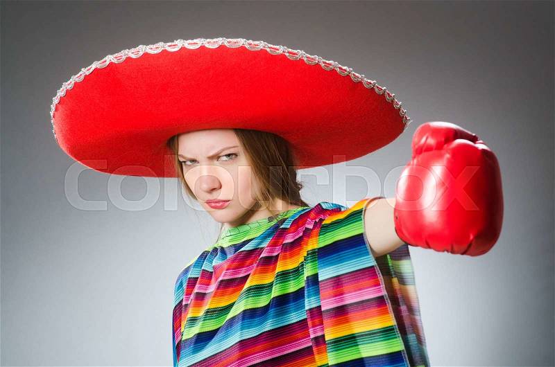 Girl in mexican vivid poncho and box gloves against gray, stock photo