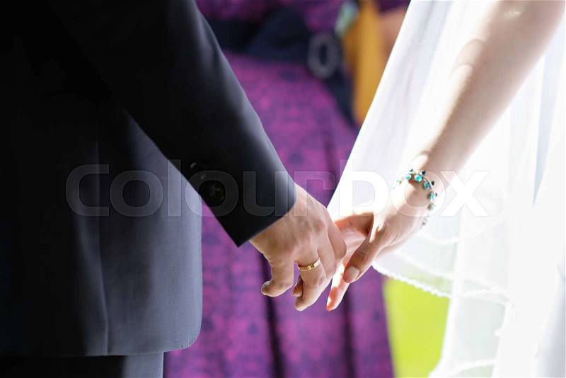 Close up photo of bride and groom holding hands, stock photo