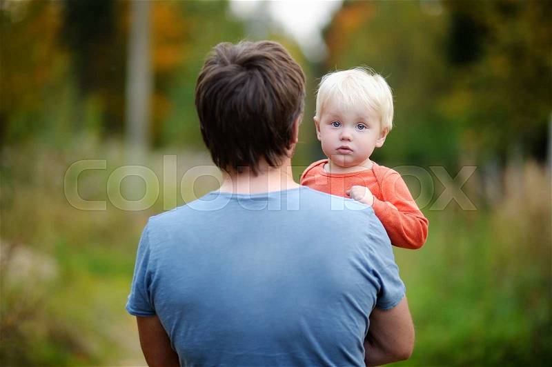 Middle age father with his toddler son walking outdoors, stock photo