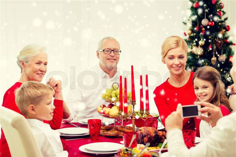 Family, holidays, generation, christmas and people concept - smiling family having dinner and making photo with camera at home, stock photo