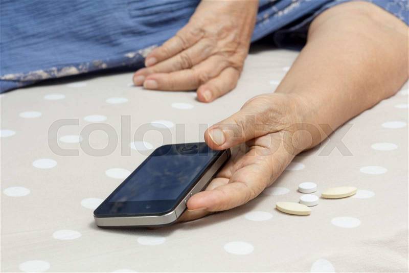 Elderly woman sleeping in bed and holding a mobile phone, stock photo