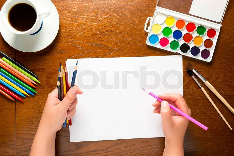Top view of a hand with pencil and blank sheet of paper, stock photo