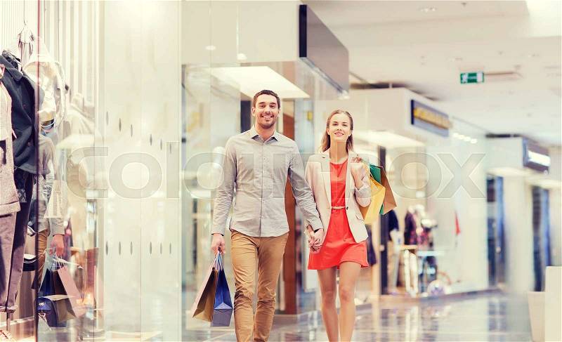 Sale, consumerism and people concept - happy young couple with shopping bags walking in mall, stock photo