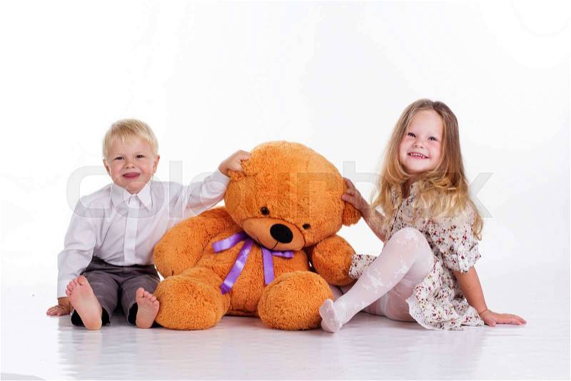 Beautiful child girl and boy are embracing big brown teddy bear, isolated on white, stock photo
