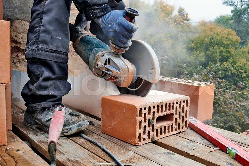 Construction worker using masonry saw to cut concrete blocks to build a new wall, stock photo