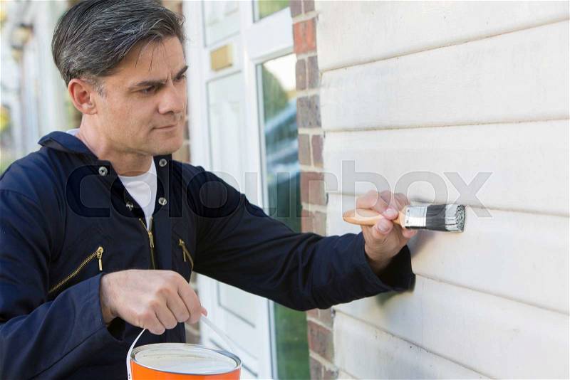 Man Holding Brush And Tin Painting Outside Of House, stock photo
