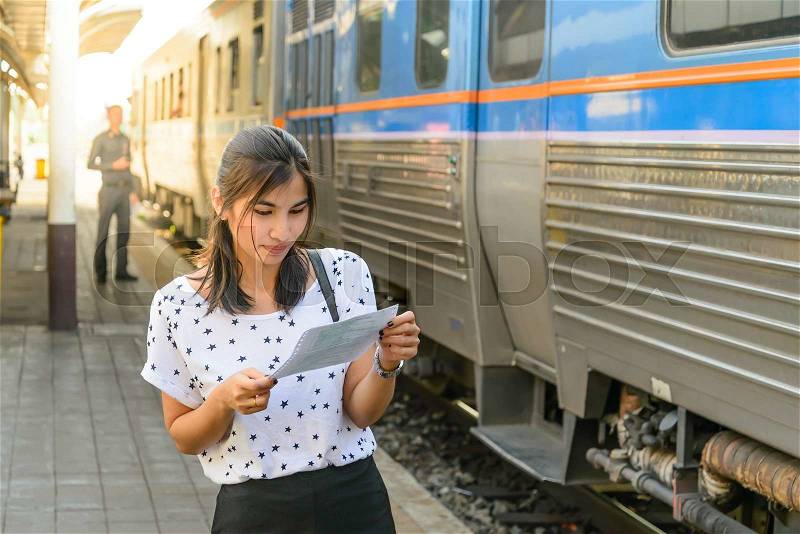Woman watching a ticket before boarding the train at platform, stock photo