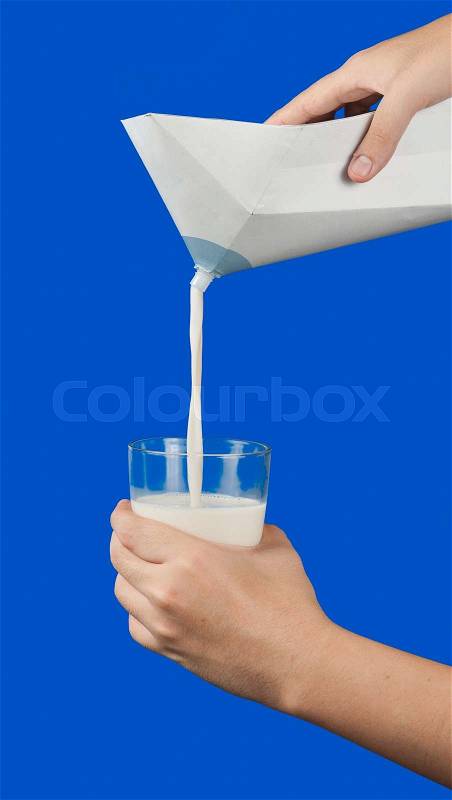 Pouring milk from a milk box in a glass on blue background, stock photo