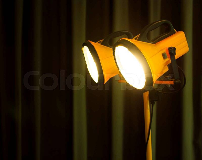 Halogen work lights on yellow tripod,dark background, stock photo