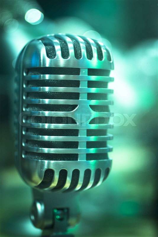 Professional retro vintage large diaphragm studio voice recording concert singing microphone showing metallic body. Artistic color digital photo with shallow depth of focus and negative space and blurred background. , stock photo