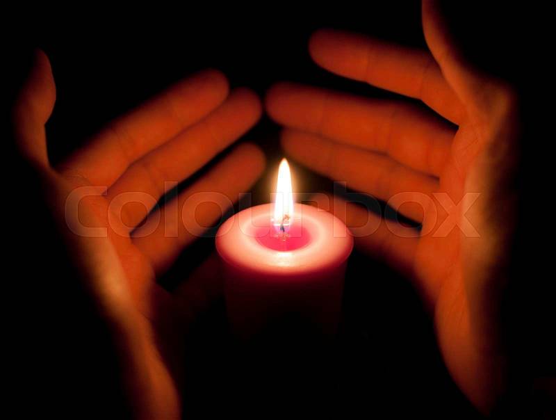Hand holding a burning candle in dark, stock photo