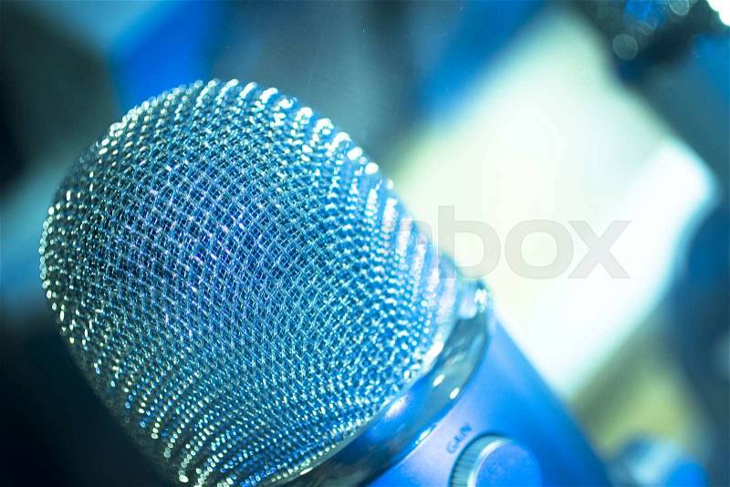 Professional studio voice recording concert singing microphone showing metallic body. Artistic color digital photo with shallow depth of focus and negative space and blurred background. , stock photo