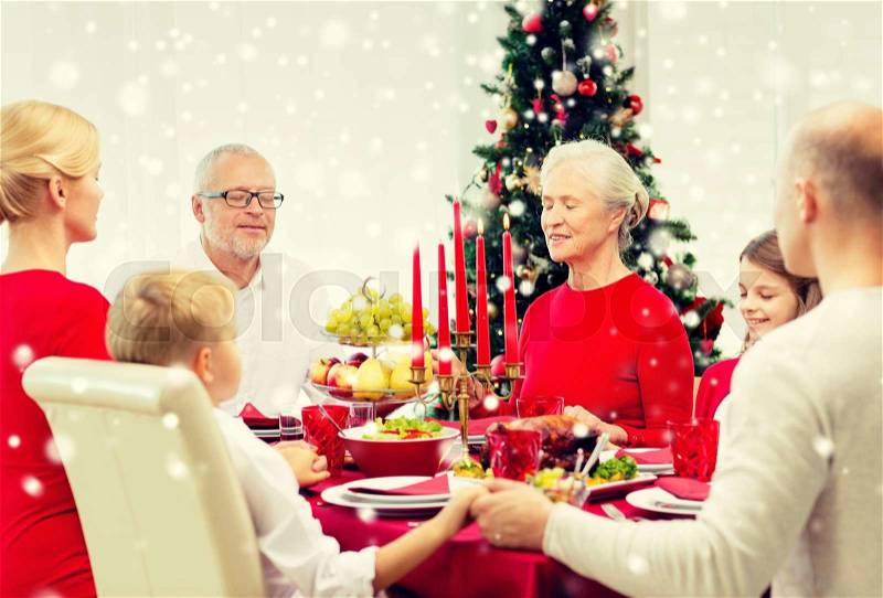Family, holidays, generation, christmas and people concept - smiling family having dinner and praying at home, stock photo