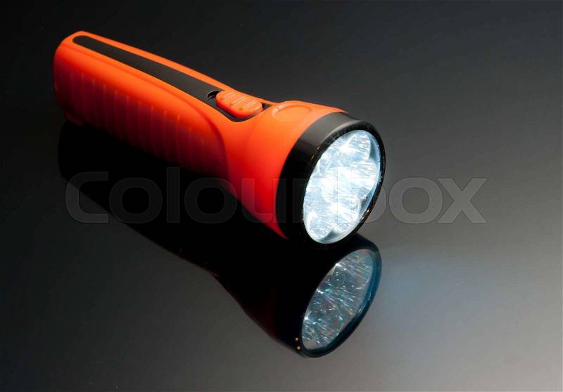 Orange led lamps flashlight plastic body on reflected glass background, stock photo
