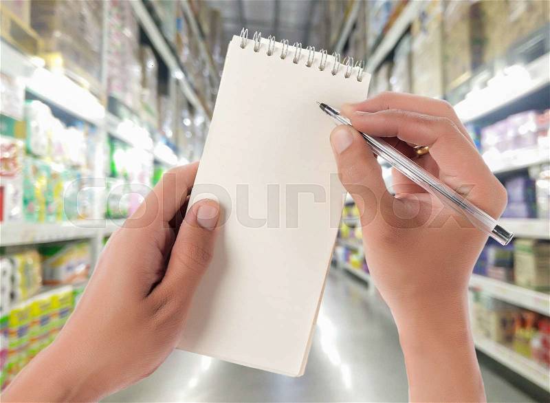 Hand hold blank notepad with space for text,Supermarket blur background, stock photo