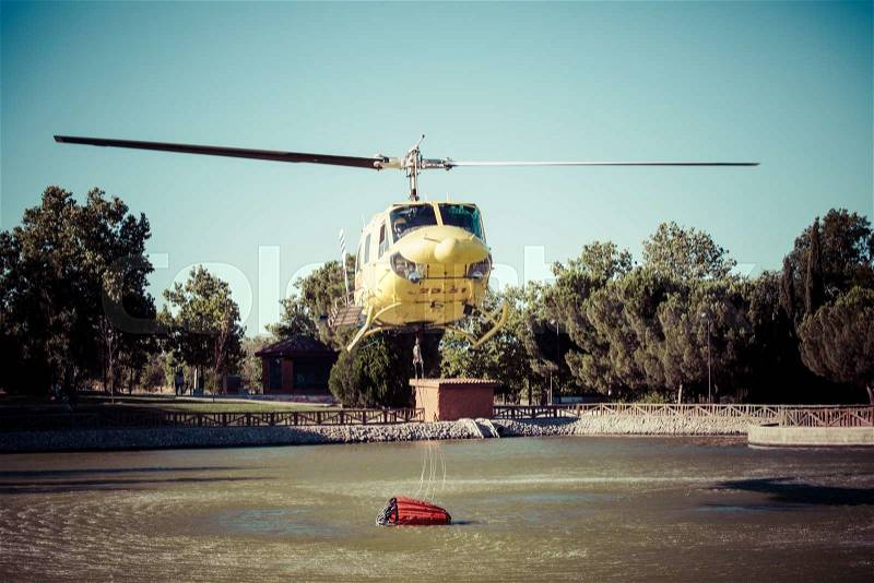 MADRID, SPAIN - AUGUST 3 : Fire rescue heavy helicopter with water bucket, goes to a fire in Madrid on August 3, 2013, Spain. , stock photo