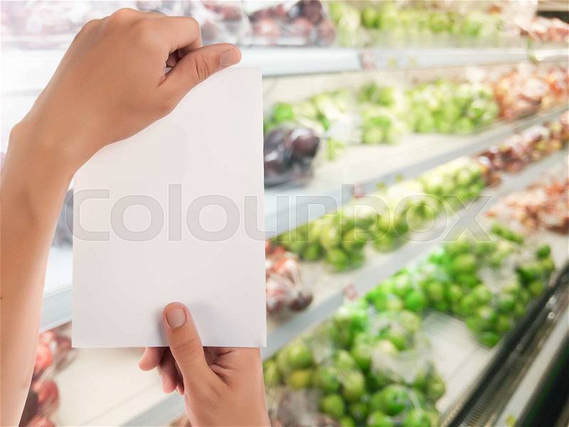 Hand hold blank notepad with space for text,Blur fruits shelf in supermarket background, stock photo