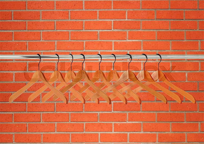 Wooden clothes hangers over orange brick wall, stock photo