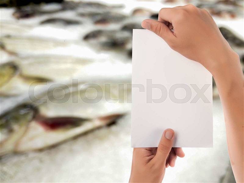 Hand hold blank notepad with space for text,blur fish on cooled market display background, stock photo