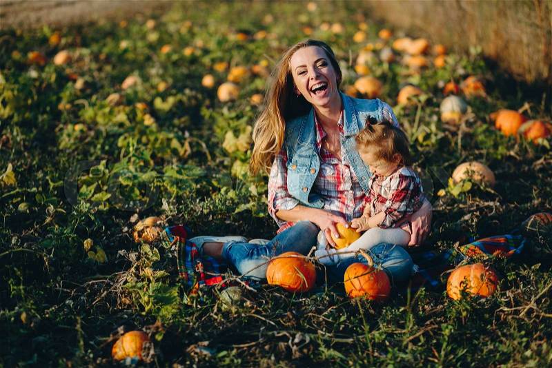 Mother and daughter on a field with pumpkins, Halloween eve, stock photo