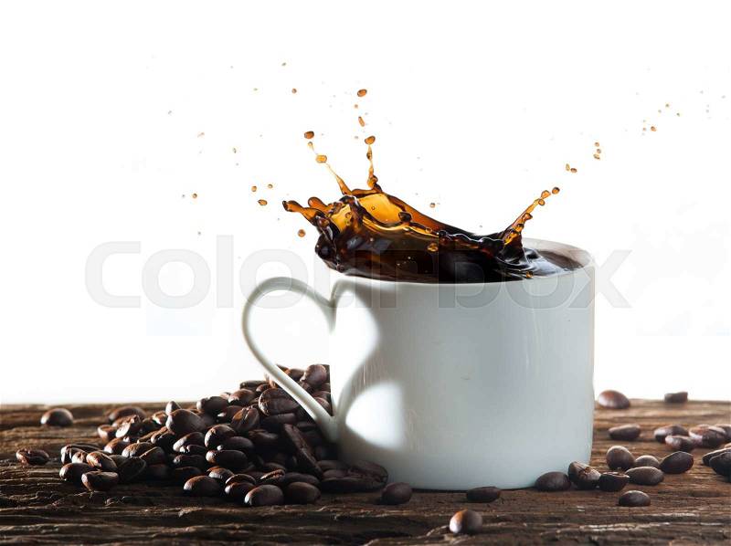 Coffee splash with heart shaped handle shadow and coffee beans on wood, stock photo