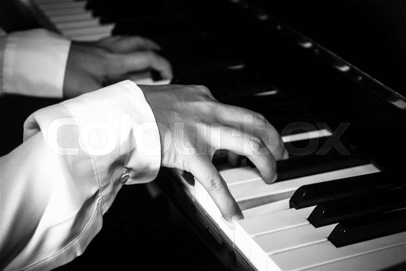 Hands of female pianist / musician playing piano B&W isolated on black for music concept, stock photo