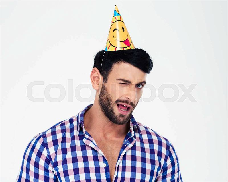 Portrait of a handsome man in birthday hat winking isolated on a white background, stock photo