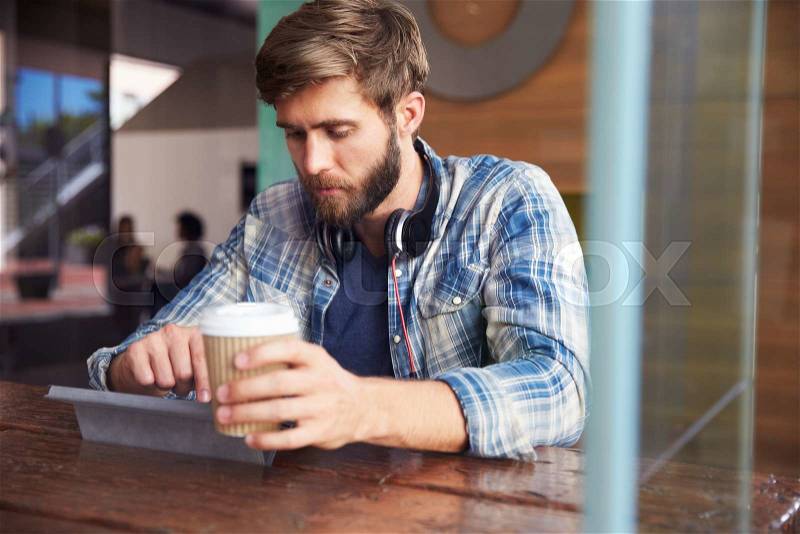 Businessman Working On Digital Tablet In Coffee Shop, stock photo