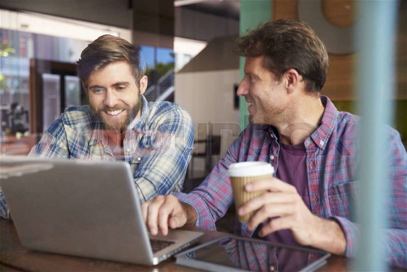 Two Businessmen Working On Laptop In Coffee Shop, stock photo