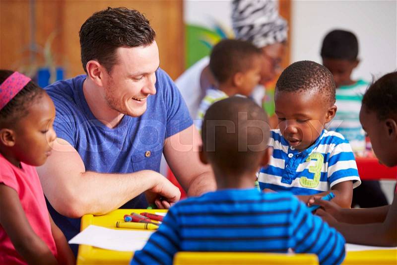 Volunteer teacher sitting with preschool kids in a classroom, stock photo