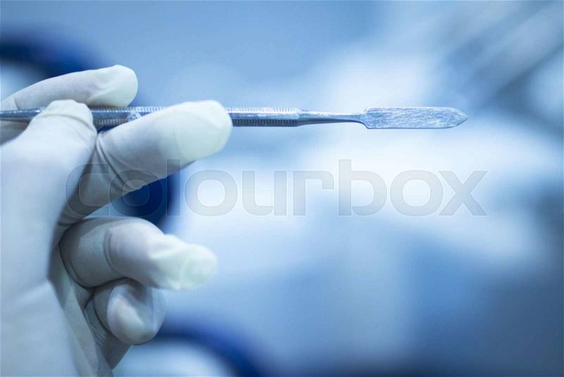 Dental instrumentation dentist tooth dental cleaning tool in the hand of dentist in dentists surgery clinic artistic color photo with shallow depth of focus, stock photo