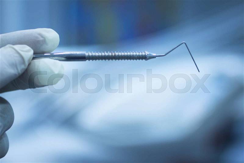 Dental instrumentation dentist tooth dental cleaning tool in the hand of dentist in dentists surgery clinic artistic color photo with shallow depth of focus, stock photo
