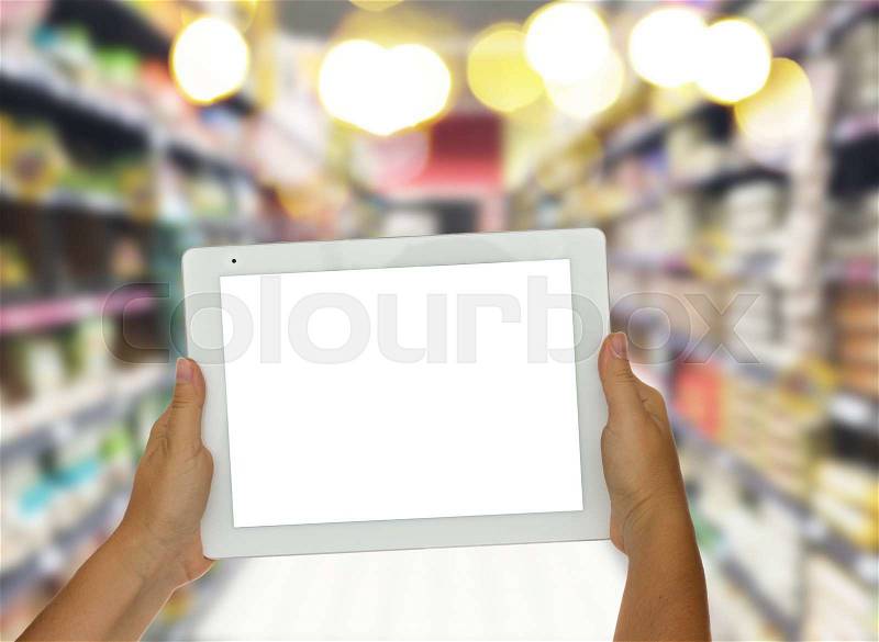 Someones hand holding tablet with empty screen on supermarket blur background business concept, stock photo