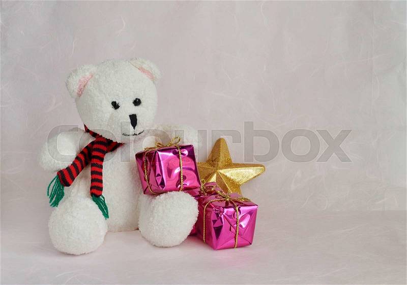 White teddy bear sitting with gift boxes on pink background, stock photo