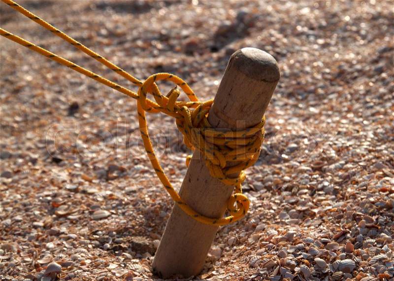 Wooden peg tent tied yellow solid thread, and scored in the sand, stock photo