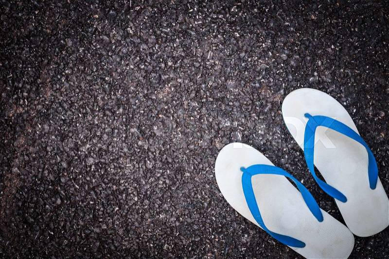 Pair of white plastic flip flop shoe on black asphalt road, stock photo