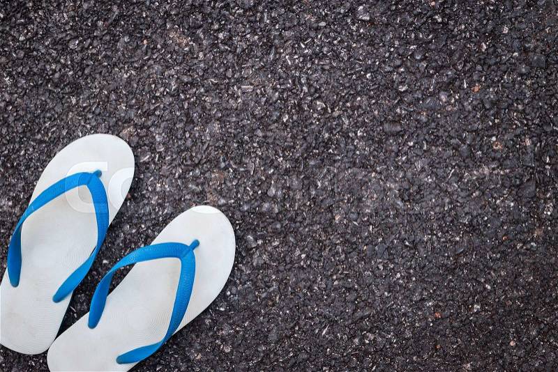 Pair of white plastic flip flop shoe on black asphalt road, stock photo