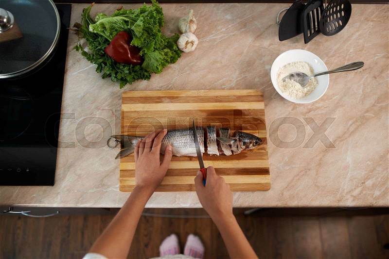 Girl cut slice of fish to cook tasty dinner, stock photo