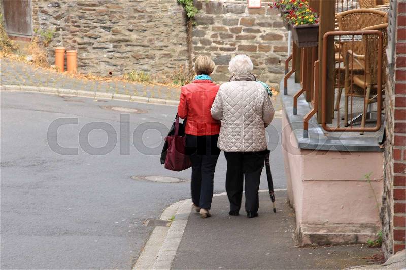 Outdoor cafe and mother and daughter are walking in one of the streets in the city Cochem in Germany in spring, stock photo