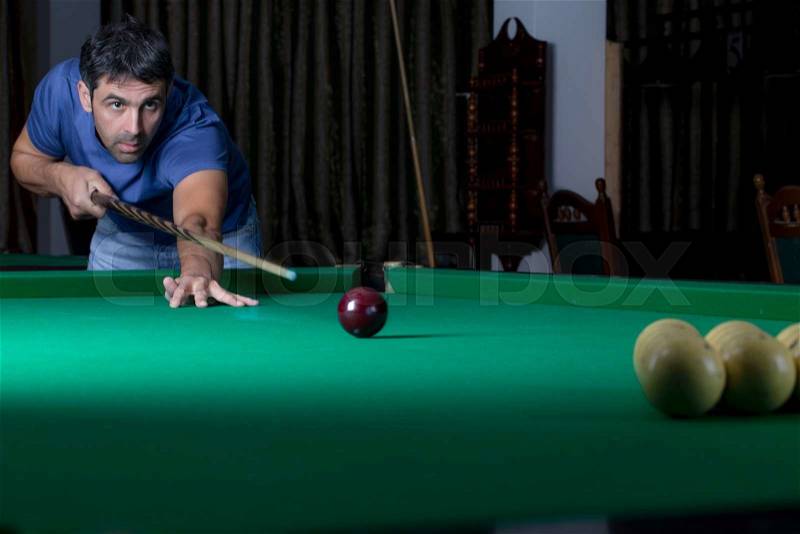 Young man lines up his shot as he breaks the balls for the start of a game of billiards, stock photo