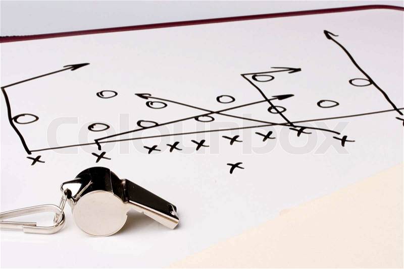 A silver whistle next to a drawing of a football play, stock photo