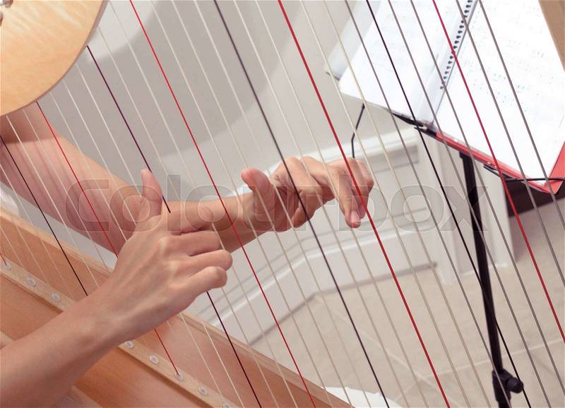 Detail of woman hands playing a harp with soft retro filter effect, stock photo