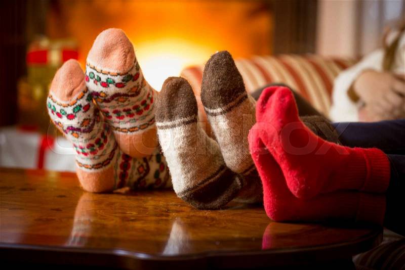 Closeup photo of family feet in wool socks at fireplace, stock photo