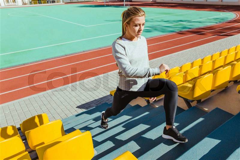 Portrait of a fitness woman doing warm up exercises at stadium, stock photo