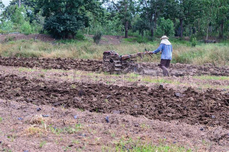 Thai farmer using walking tractors for cultivated soil for prepare plantation, stock photo
